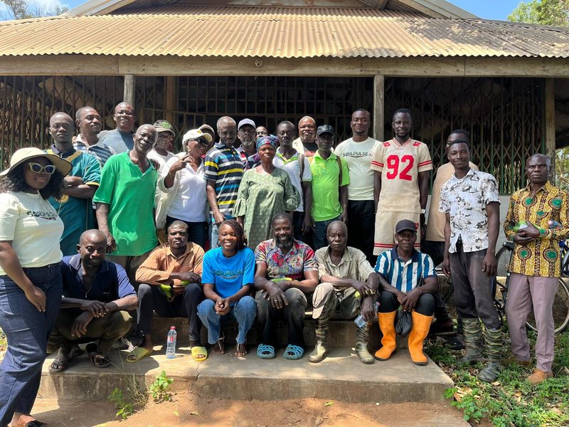 A large group of farmers gathered with the SoilPulse team outside a community building